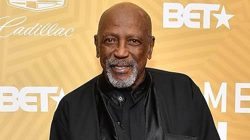 Louis Gossett Jr. at a BET event, smiling against a gold Cadillac backdrop